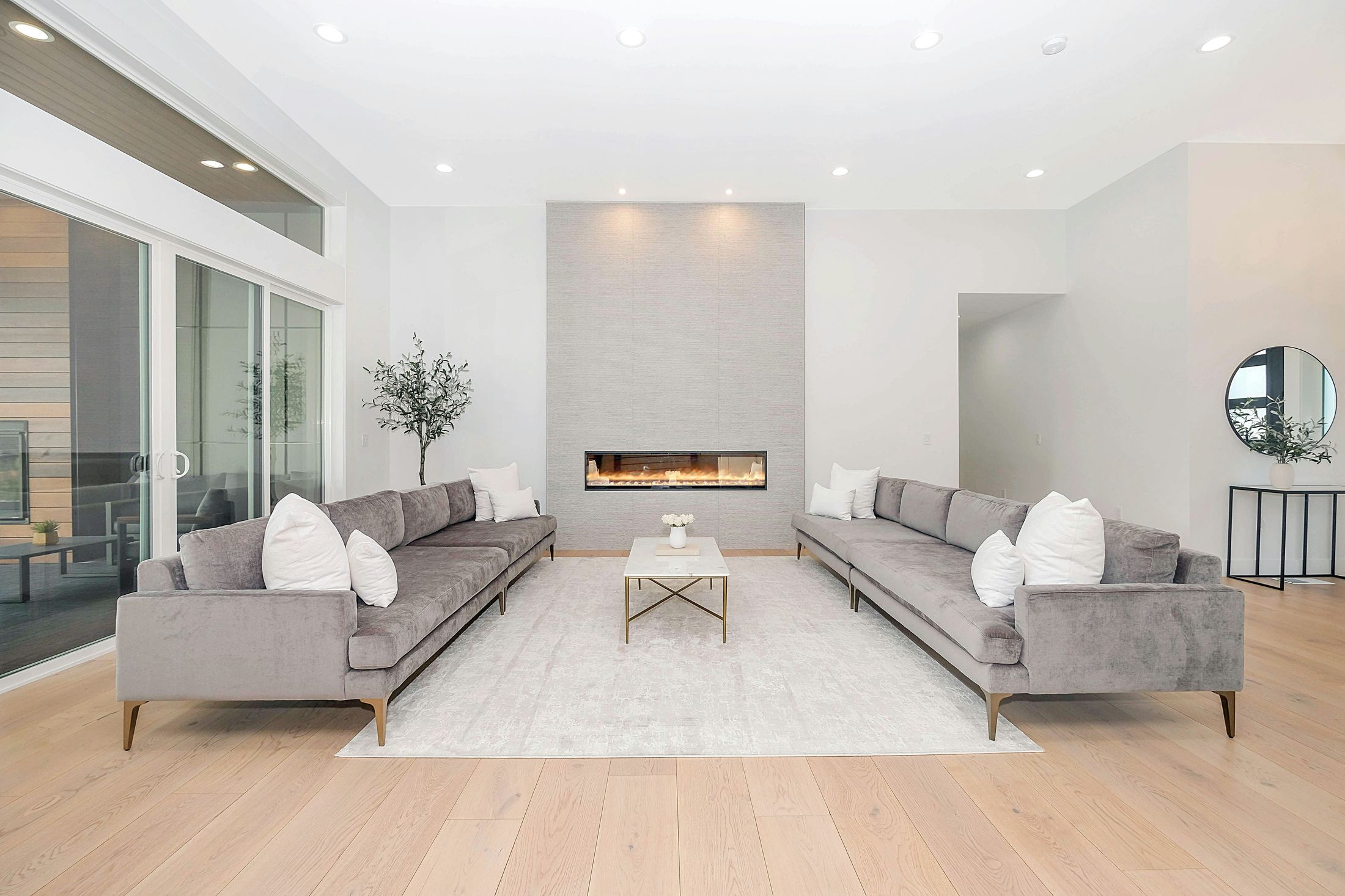 Salón contemporáneo con sofás grises y chimenea, concepto visual editorial.